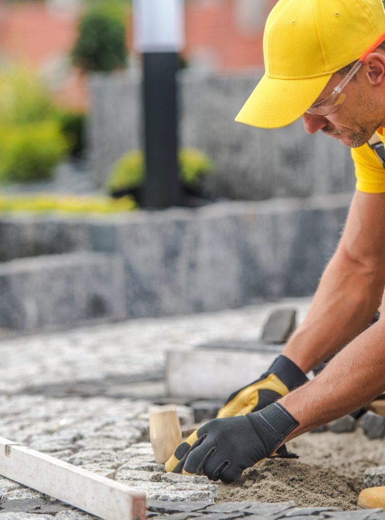 Residential Granite Brick Paving by Caucasian Construction Industry Worker.